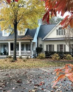 a white house surrounded by trees and leaves