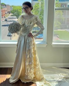 a woman standing in front of a window wearing a dress