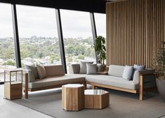 a living room filled with furniture next to large windows and a view of the city