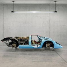 an old blue race car is parked in a garage with its hood up and engine exposed