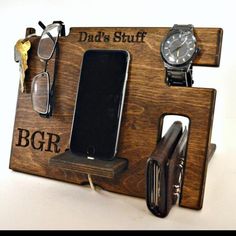 a cell phone, watch, and wallet are on a wooden sign with the words dad's stuff