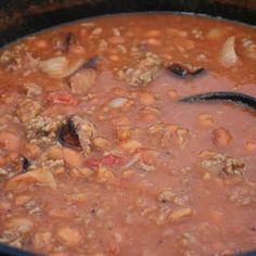 a pot filled with beans and meat on top of a stove