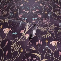 a purple floral wallpaper with small flowers and leaves on the side, as well as a roll of tape