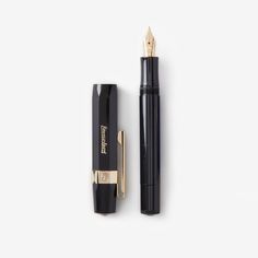 the fountain pen and its cap are next to each other on a white surface with gold trimmings