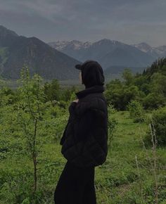 a person standing in the grass looking at mountains