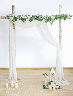 an altar decorated with greenery and candles for a wedding or special occasion in white