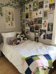 there is a bed with many pictures on the wall above it and stuffed animals in front of the bed