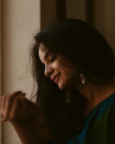 a woman looking out the window while holding her hand in her other hand and smiling