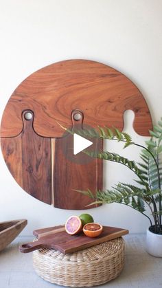 a wooden cutting board sitting on top of a table next to a potted plant