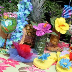 a table topped with pineapples, flowers and flip flops