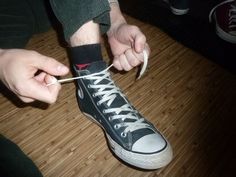 someone tying up their shoe laces with a pair of scissors on a wooden floor