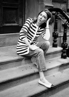 a woman is sitting on the steps with her hand under her head and looking at the camera