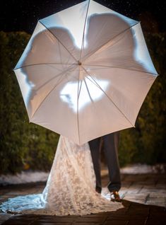 a bride and groom under an umbrella in the rain