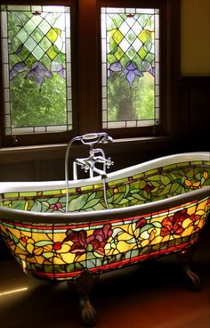 a bath tub sitting in front of two stained glass windows