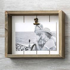 an old photo hanging on the wall next to a wooden frame with two people in it