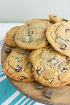 chocolate chip cookies stacked on top of each other in a wooden plate with blue and white towel