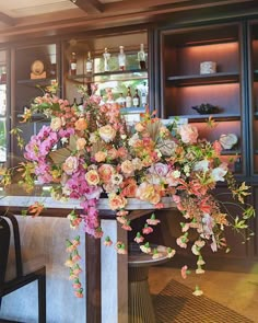 a vase filled with lots of flowers sitting on top of a counter next to a chair