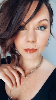 a woman with blue eyes and piercings on her nose is posing for the camera