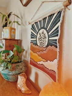 a wooden table topped with a potted plant next to a wall hanging