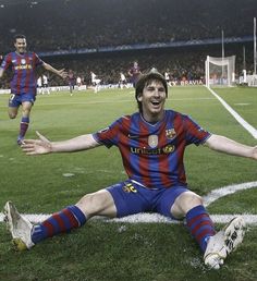 a man sitting on top of a soccer field with his arms out in the air