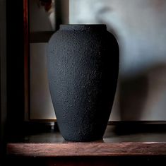 a black vase sitting on top of a wooden table