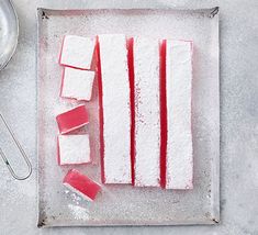 red and white sugar cubes sitting on top of a baking sheet next to a spatula