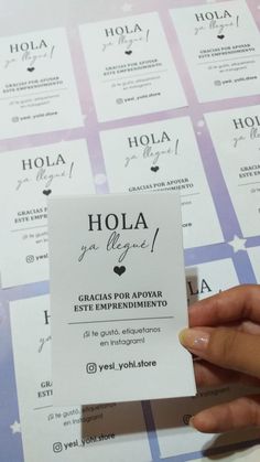 a person holding up a business card with the word hola on it