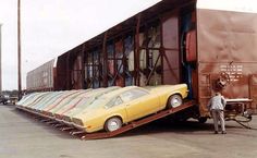 a man standing next to a yellow car on the back of a truck