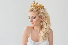 a woman with blonde hair wearing a tiara and looking off to the side, against a white background