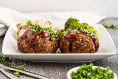 two meatballs covered in ketchup on a plate with broccoli