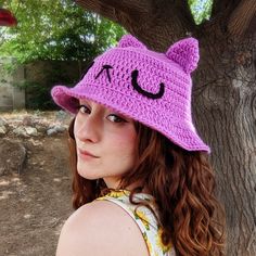 a woman wearing a purple crocheted hat with a smiley face