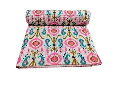 a pink and blue patterned blanket on top of a white background