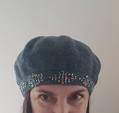 a close up of a person wearing a knitted hat with beaded trims