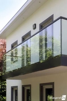 an image of a balcony with glass railings on the outside and trees in the background