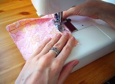 a woman is using a sewing machine to sew something on a piece of fabric