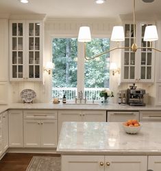 a large kitchen with white cabinets and marble counter tops, along with an island in the middle