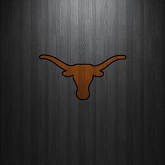 the texas longhorns logo is shown on a wooden wall with dark wood grain