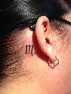 a woman's ear with the word mom tattooed on her left behind the ear