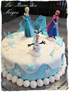 there is a cake with frosting on it that has frozen princess figures on top