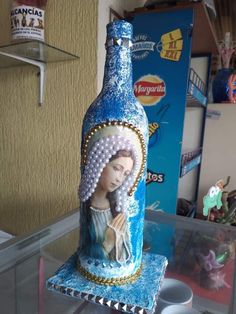 there is a bottle that has been decorated with beads and pearls on the bottom, sitting on a glass table