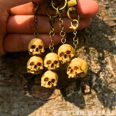 a person holding five small skulls in their hands with chains hanging from them on the ground