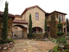 a stone house with trees and bushes around it