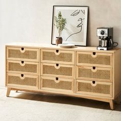 a wooden dresser with drawers and a coffee maker on top of it next to a painting