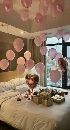 balloons are floating from the ceiling above a bed