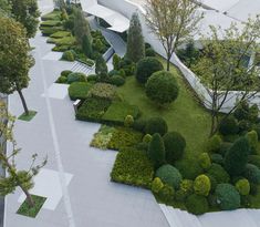 an aerial view of a garden with trees and bushes in the foreground, surrounded by concrete walkways