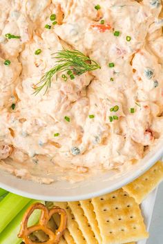 a white bowl filled with dip surrounded by crackers and celery