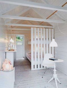 a white room with a bed and desk inside of it on top of a hard wood floor