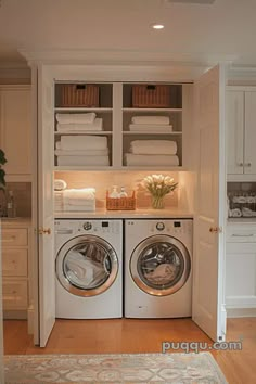 a washer and dryer in a small room with white cabinets on the wall