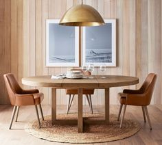 a dining room table with two chairs and a lamp hanging over it in front of wooden paneled walls