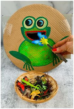 a paper plate with a green frog on it and a basket full of small toys